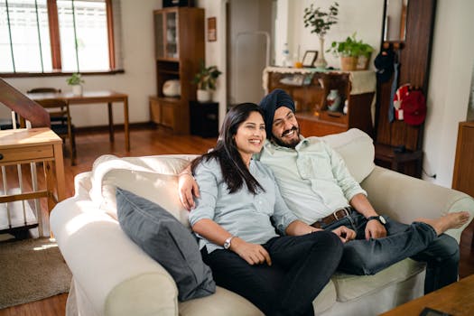 Smiling couple enjoying a cozy day indoors on a comfortable sofa in a modern living room.